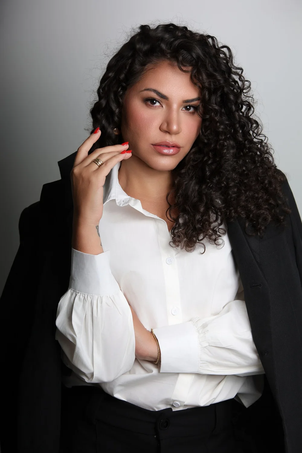 Dra. Camilla Ferreira em retrato profissional, com camisa branca e blazer preto